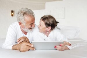 happy couple in bed using laptop